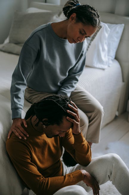 A couple showing emotional support and connection in a bedroom environment.