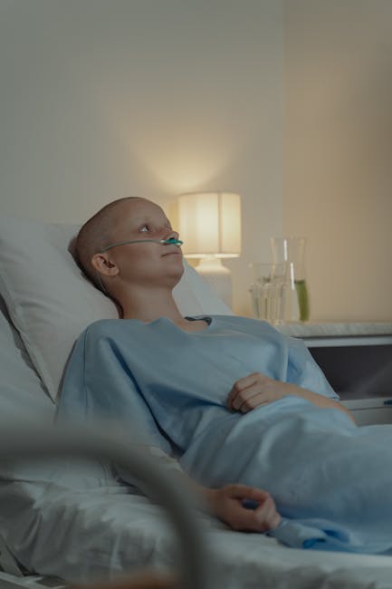 Bald woman in hospital bed receiving oxygen support, showing resilience in illness.
