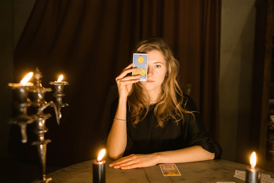 A woman in dim candlelight holding a tarot card, creating a mystical ambiance.